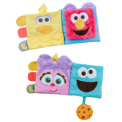 An layout view of the open Sesame Street cloth book pages displaying bright character spreads and a dangling textured cookie teether.
