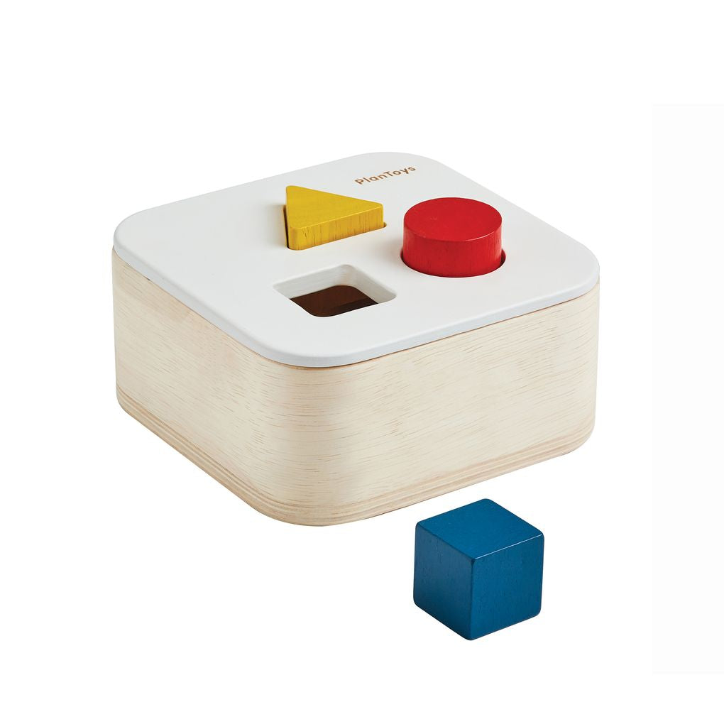 The PlanToys wooden shape sort it out bin featuring falling colorful geometric blocks in star, circle, triangle, and square shapes.
