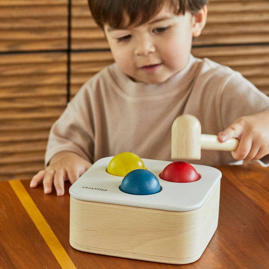 A close-up of a toddler happily playing with the eco-friendly PlanToys pounding toy.