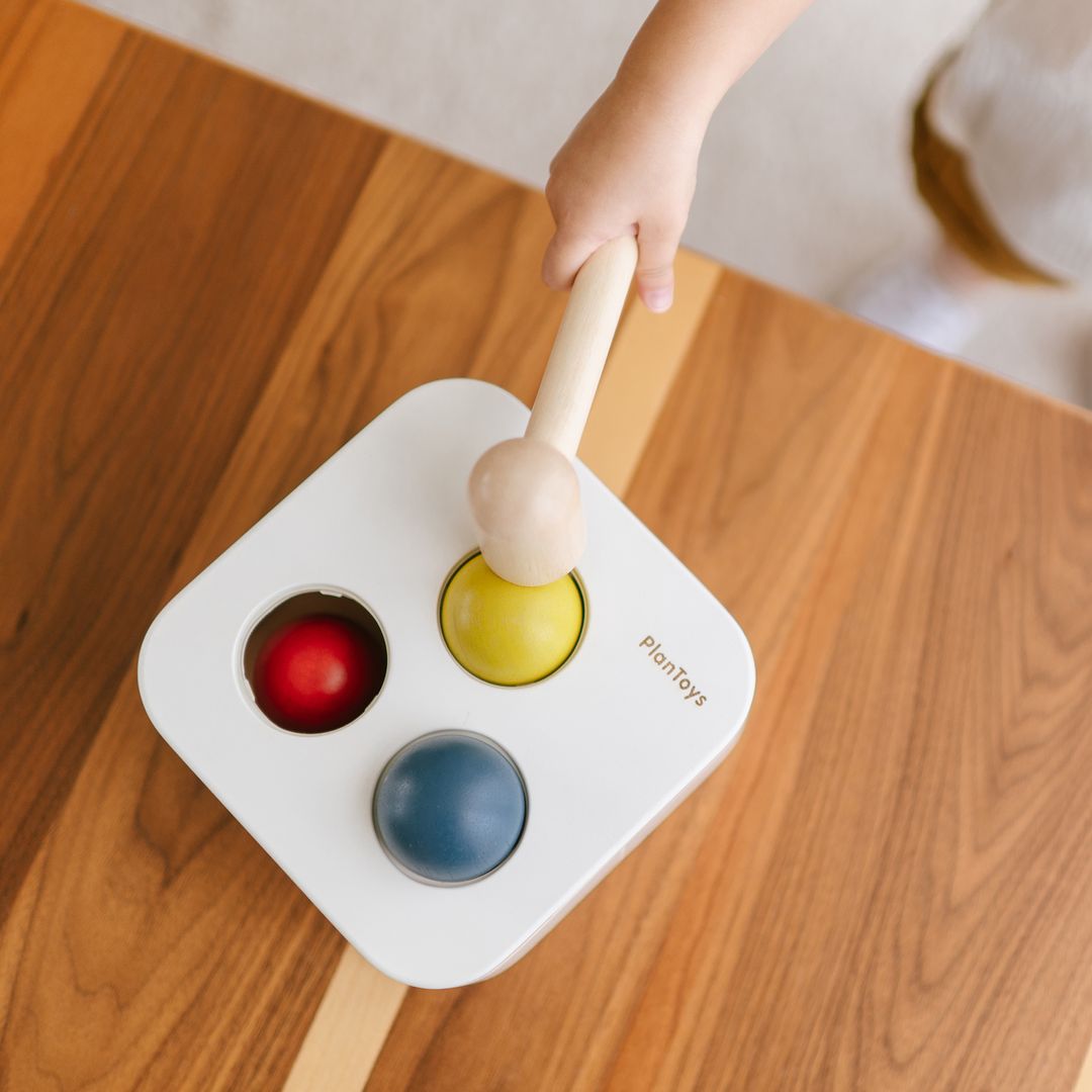 Lifestyle shot of a child pounding the wooden ball of the PlanToys cause-and-effect toy.