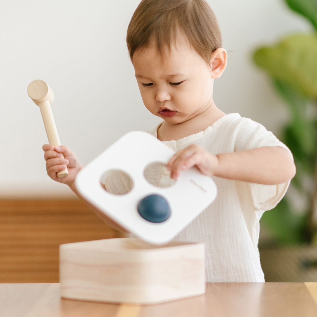 Close angle of a young child engaged in hands-on play with the sustainable rubberwood pounding box.