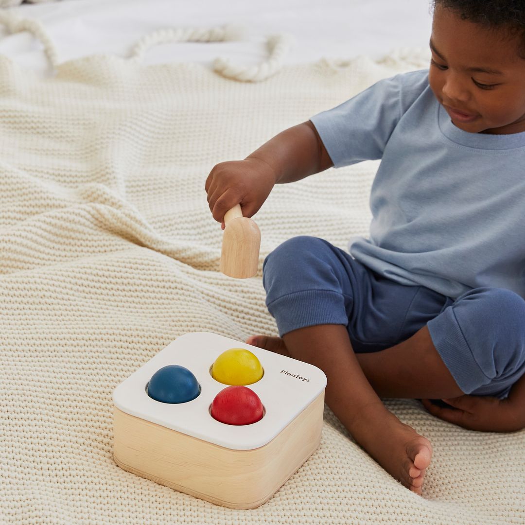 A little one practicing hand-eye coordination with the PlanToys wooden hammer and balls.