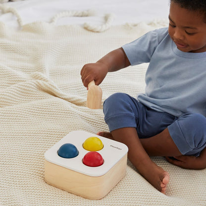 A little one practicing hand-eye coordination with the PlanToys wooden hammer and balls.