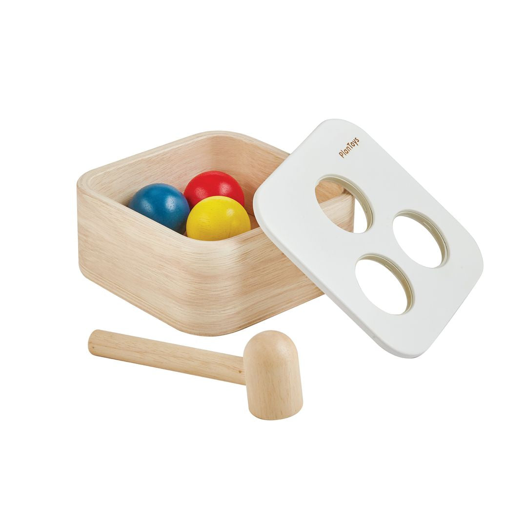 All components of the PlanToys Punch and Drop set, including the wooden box, three colored balls, and hammer.