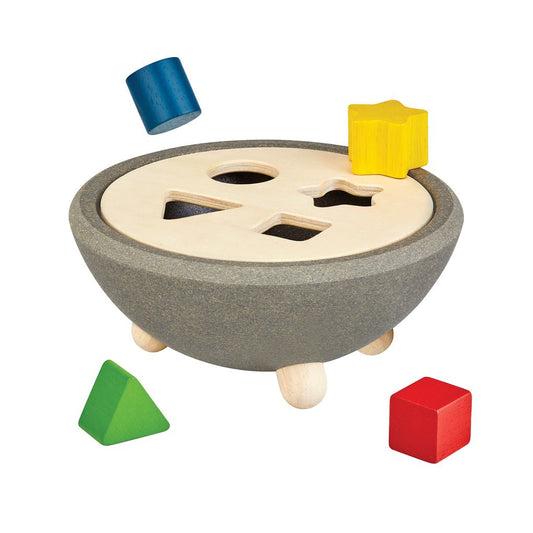 The PlanToys wooden shape sorting bowl featuring falling colorful geometric blocks in star, circle, triangle, and square shapes.