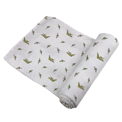 Angled view of the swaddle blanket partially unrolled to showcase the flying green dinosaur pattern.