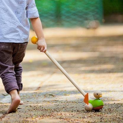 Close angle of a young child exploring cause-and-effect movement with their cheerful PlanToys wooden duck.