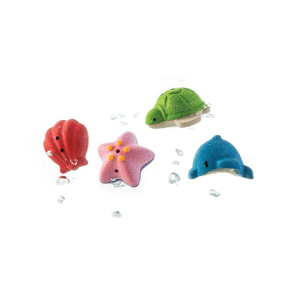 The sustainable PlanWood pink starfish, green turtle, blue dolphin, and red shell floating with water splashing around them.
