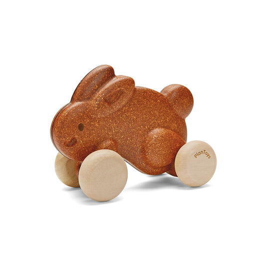 Front angle of the textured brown PlanToys wooden push along bunny toy with smooth natural wood wheels.