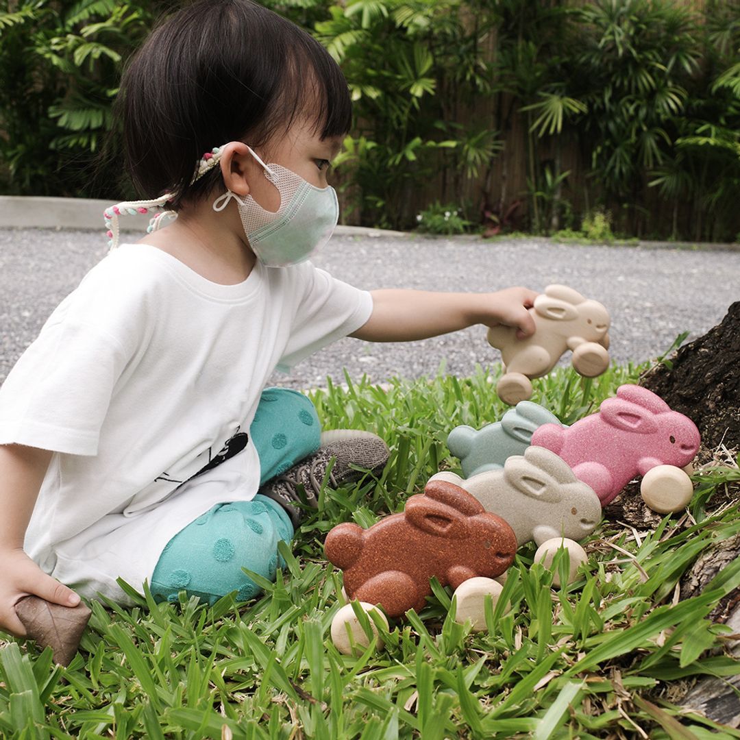 Lifestyle shot of a little one holding the earth-friendly PlanToys rabbit, perfect for encouraging active crawling play.