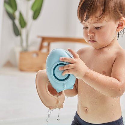 A toddler pulling apart the top and bottom pieces of the PlanToys rubber convertible boat in the bathtub.