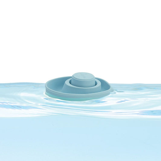 The PlanToys pastel blue flexible rubber convertible boat floating smoothly on clear water.
