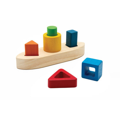Isolated view of the PlanToys sorting boat showing the red triangle and blue square blocks removed from their pegs.