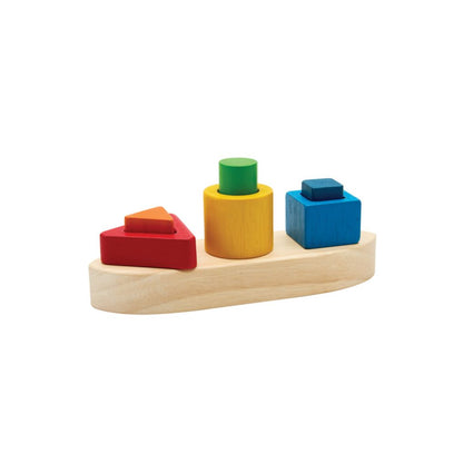 Front view of the eco-friendly PlanToys wooden shape sorting boat featuring nested red, blue, green, and yellow blocks.
