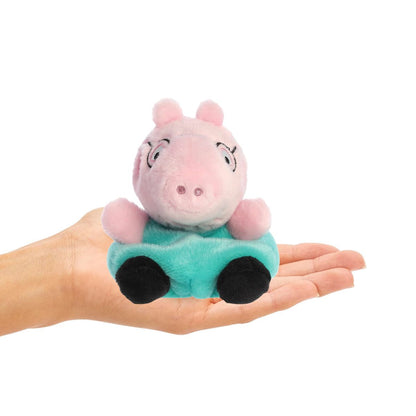 Small plush toy of a pink pig in a green shirt held in a hand on a white background
