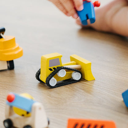 A single PlanToys wooden toy car resting on a playroom floor, ready for fast-paced action.