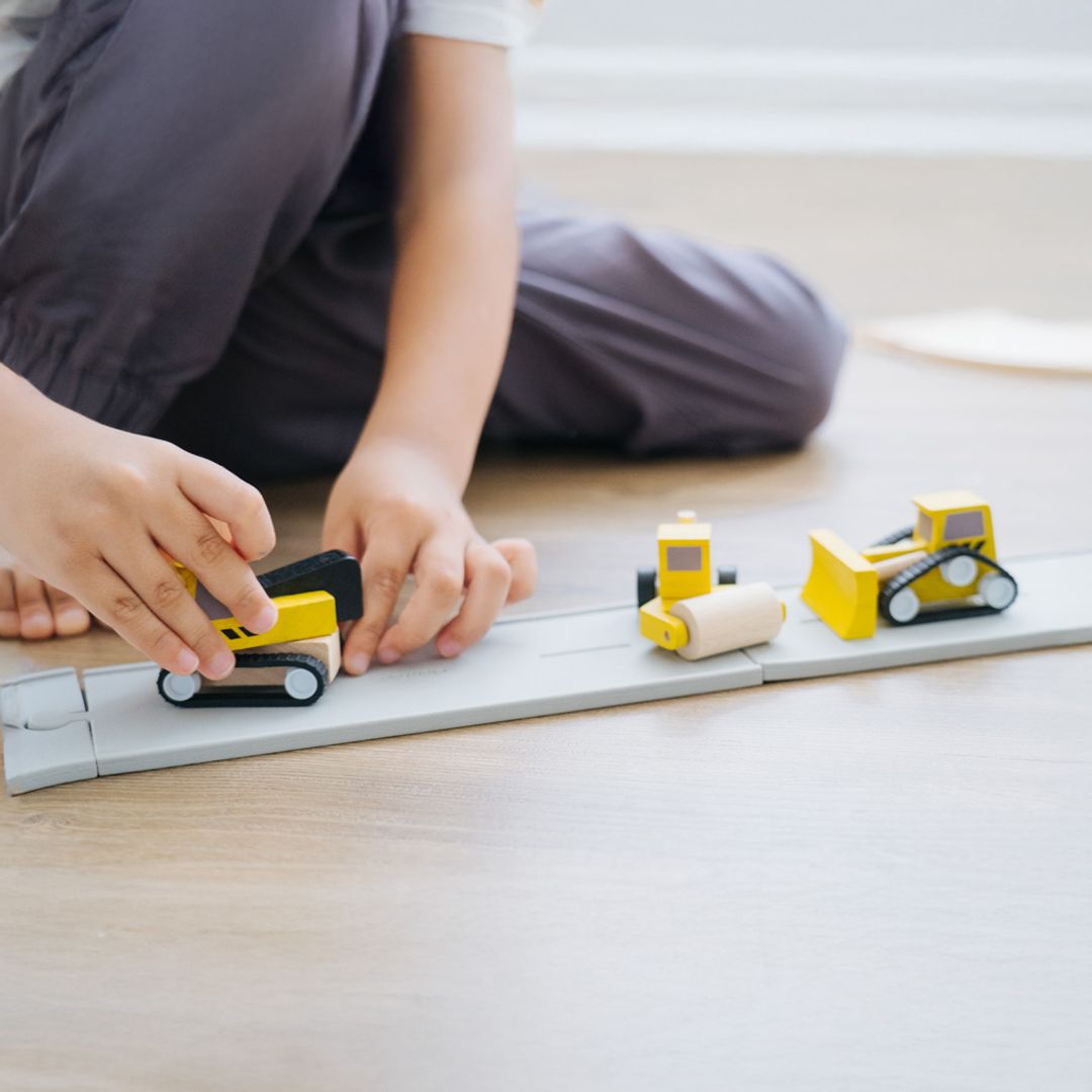 Overhead view of a child sitting on the floor and driving their earth-friendly PlanToys vehicle.