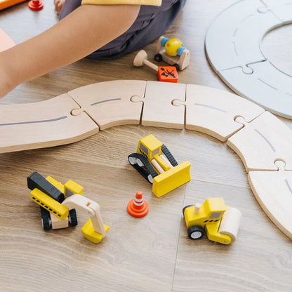 The vibrant PlanToys wooden car driving alongside a matching wooden road track setup.