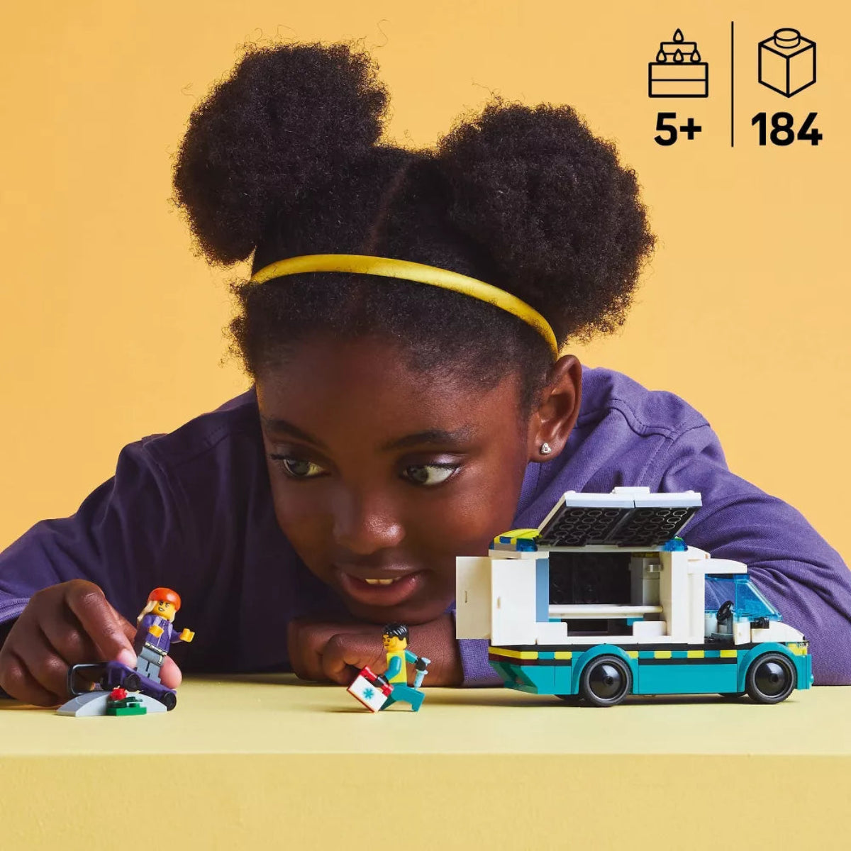 Child playing with a toy vehicle and figures on a yellow background