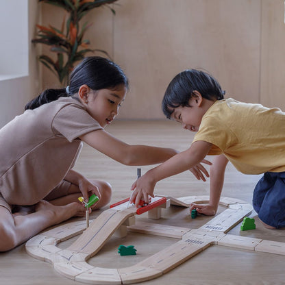 Children connecting the interlocking puzzle-like tracks of the PlanToys road playset.