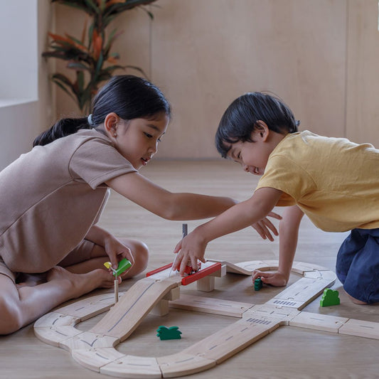 Children connecting the interlocking puzzle-like tracks of the PlanToys road playset.