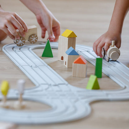 Children's hands connecting the interlocking pieces of the eco-friendly PlanToys natural rubber road toy.