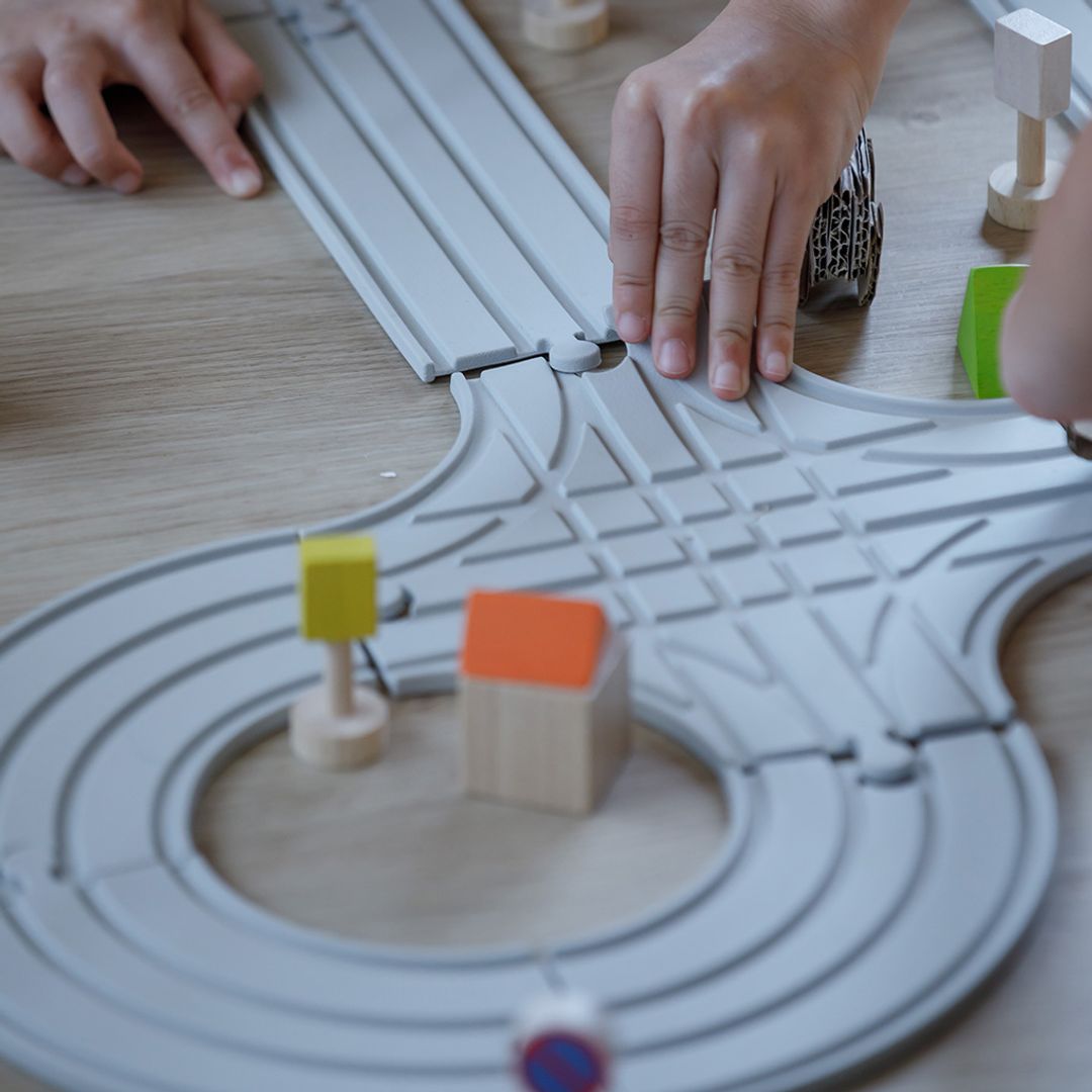Detailed view of the flexible toy road tracks and sustainable wooden accessories in the PlanToys medium set.