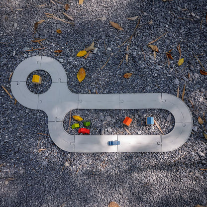 The durable, waterproof PlanToys rubber road set laid out outside on a dirt and gravel path.