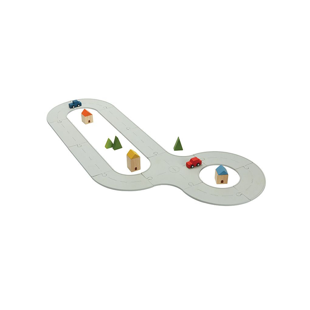 The fully assembled PlanToys flexible rubber road and rail medium set featuring wooden cars, houses, and trees.