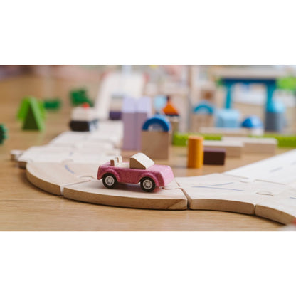 PlanToys wooden pink sports car across a child's wooden track.