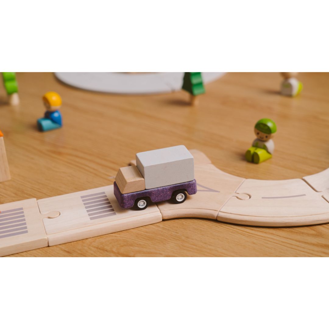 Lifestyle image of PlanToys wooden purple delivery truck toy.