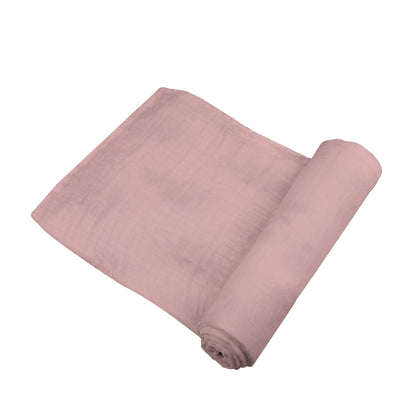 Angled view of the solid pink Pink Rose bamboo muslin swaddle blanket partially unrolled to show its soft texture.