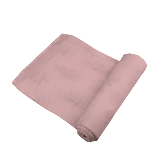 Angled view of the solid pink Pink Rose bamboo muslin swaddle blanket partially unrolled to show its soft texture.
