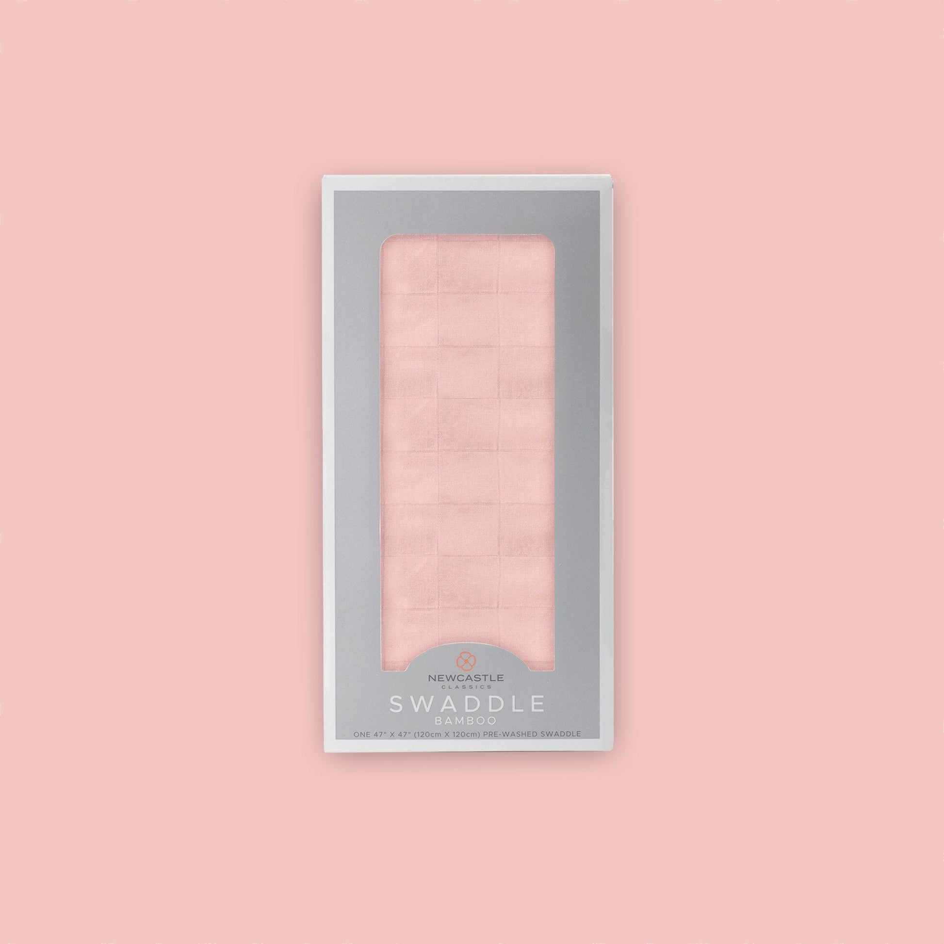 Straight front view of the packaged Newcastle Classics Pink Rose bamboo muslin swaddle blanket in a grey window box set against a matching solid pink background.
