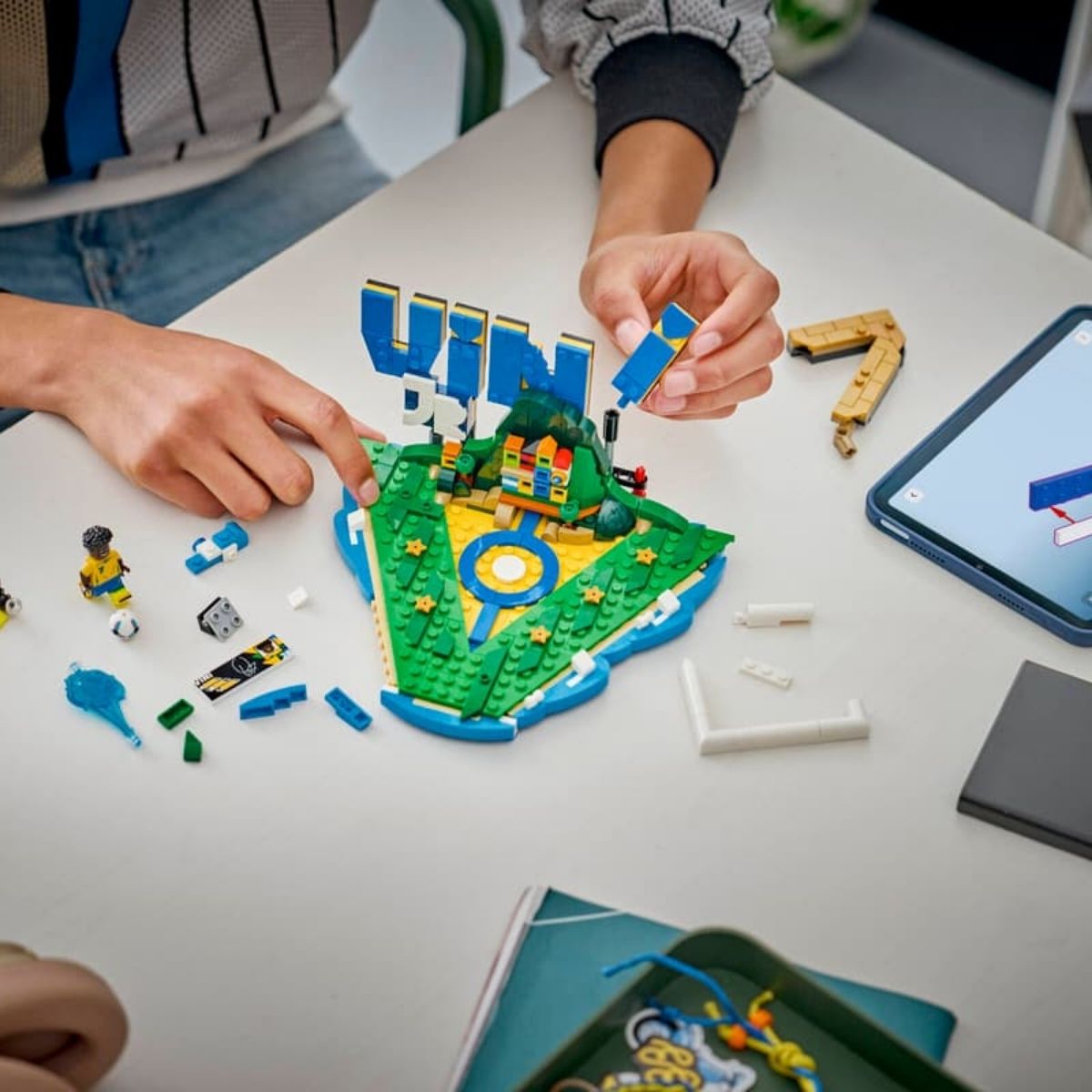 Lifestyle view of a child using a digital tablet running the LEGO Builder app to assemble the pieces of the Vini Jr. highlights set.