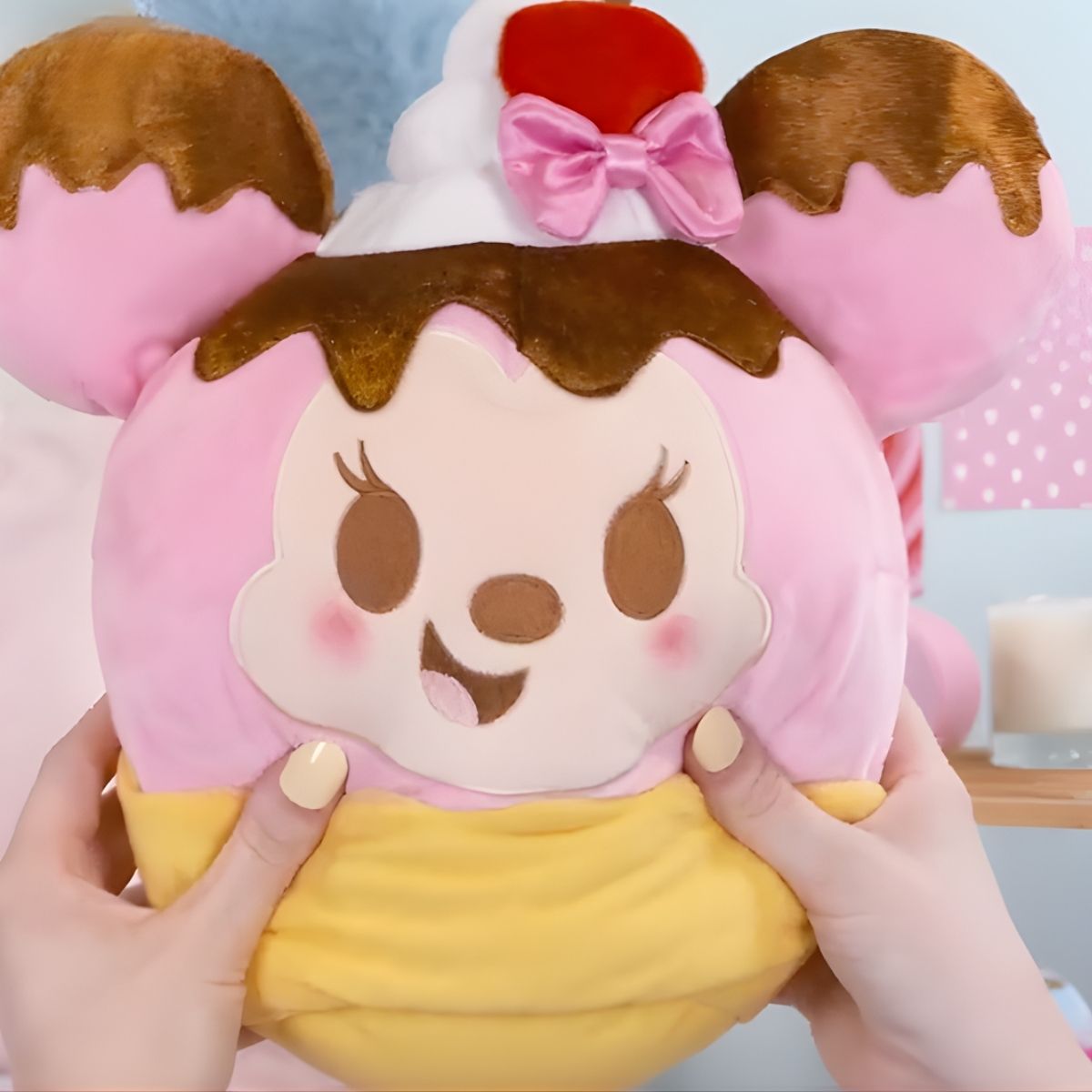 Lifestyle image showing a person's hands gently squeezing the ultra-squishy 10-inch Disney Munchlings Squeeze-A-Munch Minnie Mouse plush.