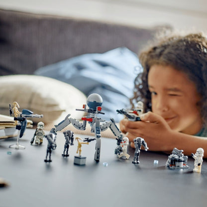 A young child smiling while playing with the assembled LEGO® Star Wars Clone Trooper and Battle Droid vehicles on a tabletop.