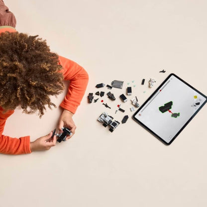 An overhead shot of a young child sitting on the floor assembling the 119-piece Imperial battle pack next to a digital tablet.