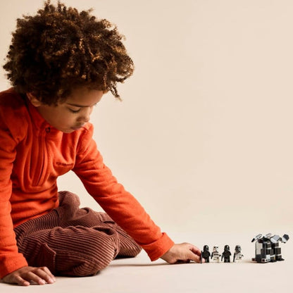 A child laying down on a carpeted floor posing and playing with the completed LEGO® Star Wars trooper figures.