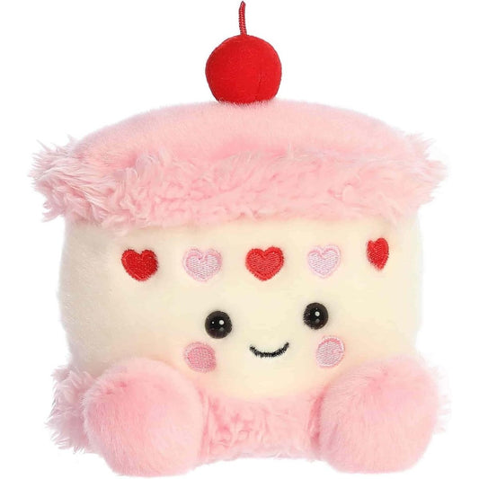 Angled front view of the 5-inch Aurora Palm Pals Jubi Heart Cake white and pink plush toy with a cherry on top.