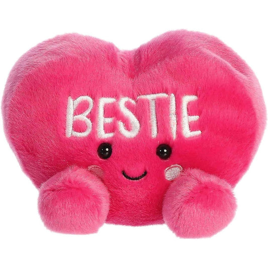 Straight front view of the sitting pink plush heart showing the embroidered BESTIE text, black eyes, and rosy pink cheeks.
