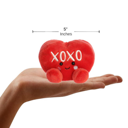 Sizing graphic showing the 5-inch Palm Pals XOXO Candy Heart plush sitting perfectly in the palm of a hand to demonstrate its small scale.