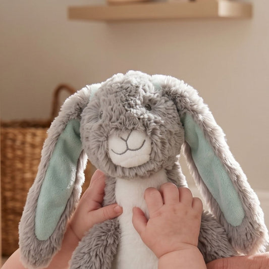 A baby's tiny hands reaching up to squeeze and play with the Happy Horse Rabbit Twine plush stroller activity toy.