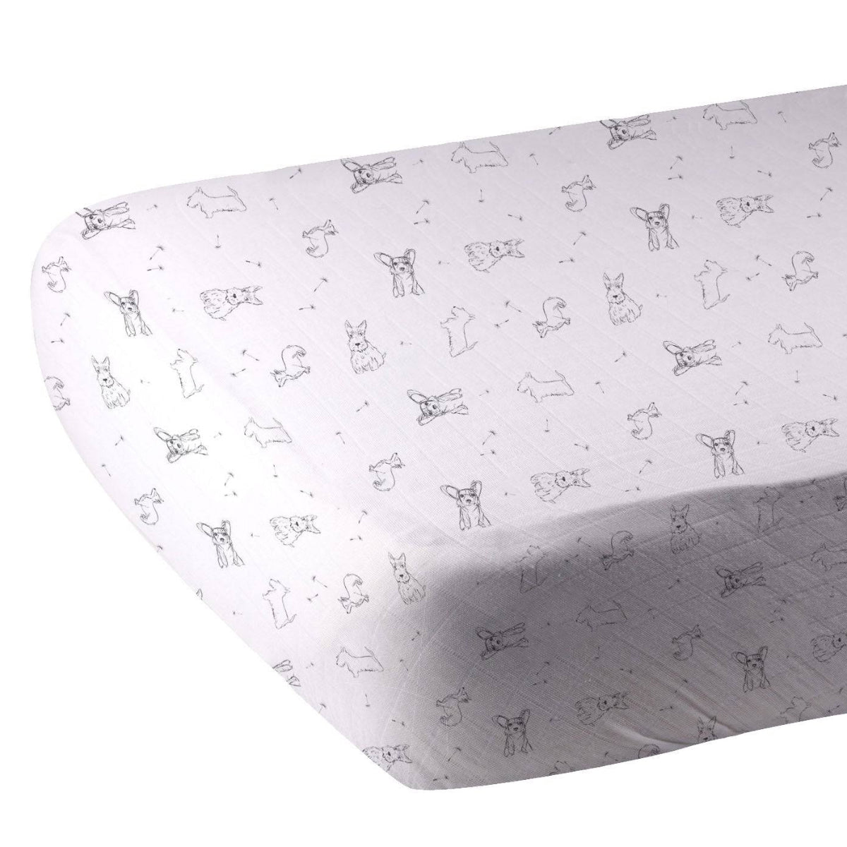 Close-up of the black and white dog print bamboo muslin fabric showing the fitted corner of the 28x52 crib sheet.