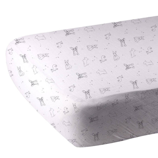 Close-up of the black and white dog print bamboo muslin fabric showing the fitted corner of the 28x52 crib sheet.
