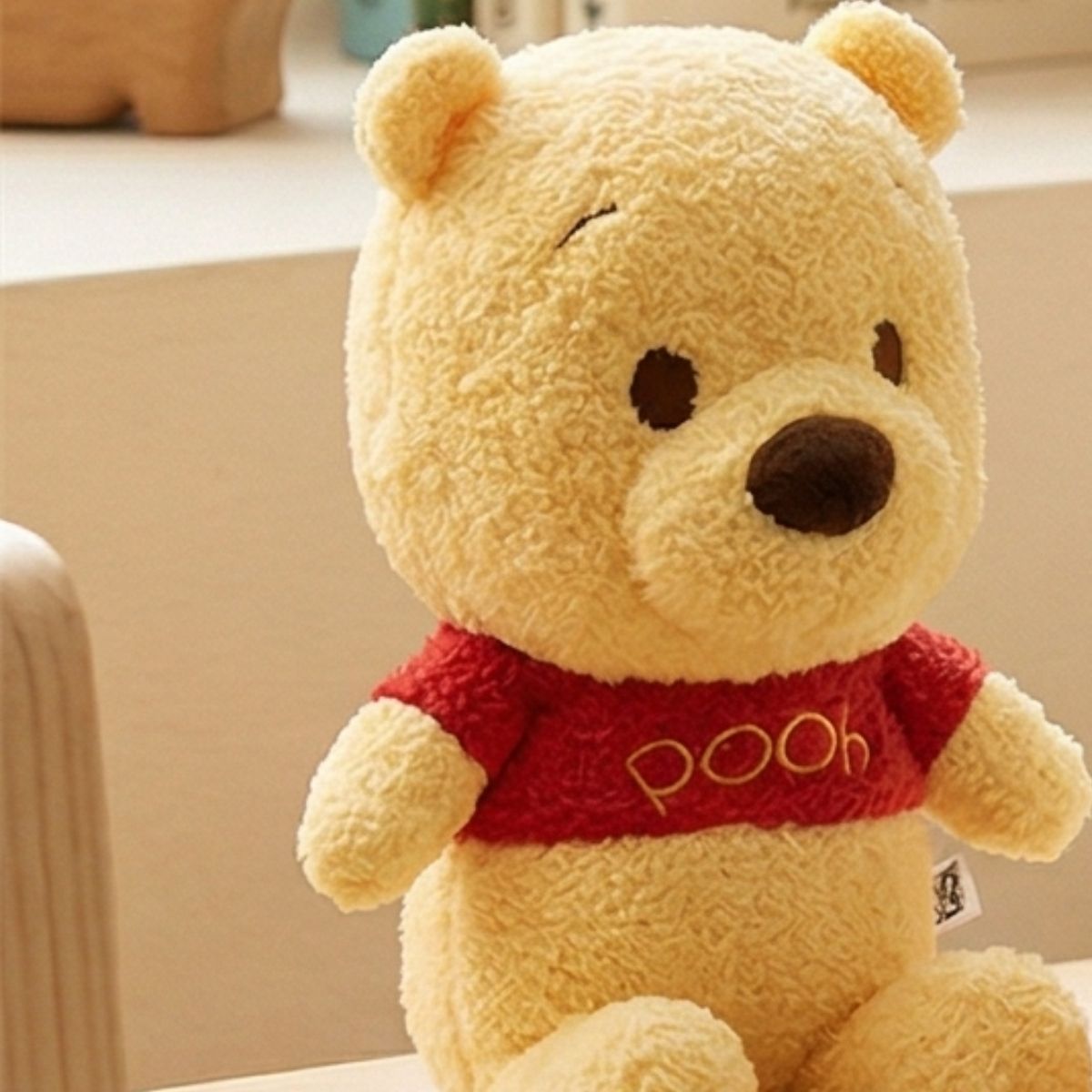 Lifestyle view of the adorable Disney Baby Winnie the Pooh stuffed animal resting in a sitting position in a softly lit nursery setting.