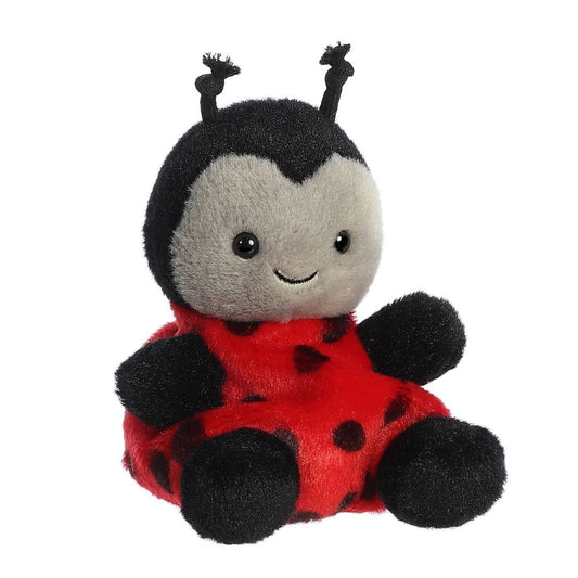Aurora 5-inch Palm Pals Lil Spots Ladybug plush toy sitting at an angle showing its vibrant red body with black spots, black head with knotted antennae, and a gray face patch with a sweet smile.