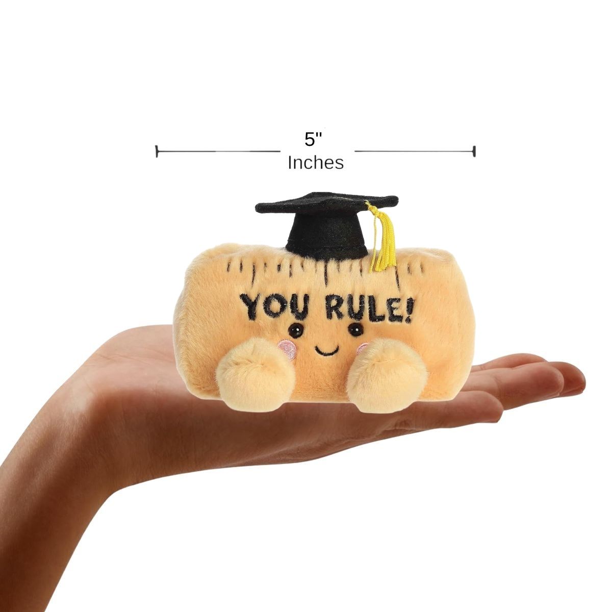 Sizing graphic showing the 5-inch Palm Pals graduation ruler plush sitting perfectly in the palm of a hand to demonstrate its small scale.