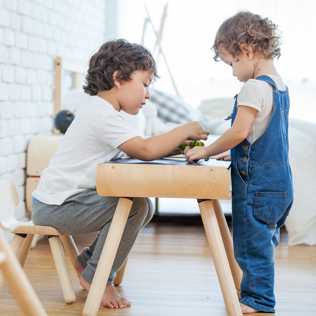 Two boys sharing space and playing together on the heavy-duty PlanToys black-top wooden playroom table.