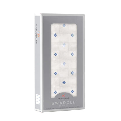 Angled front view of the Newcastle Classics baby swaddle blanket folded inside a light grey window display box.